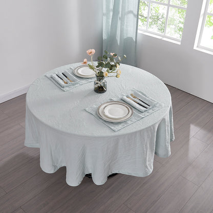 Top angle of 100% linen round tablecloth in pale blue draped over a round table set with plates and cutlery