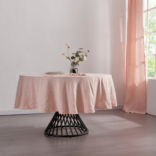 A 100% linen round tablecloth in peach draped over a round table