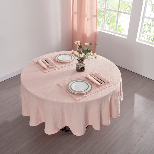 Top angle of 100% linen round tablecloth in peach draped over a round table set with plates and cutlery