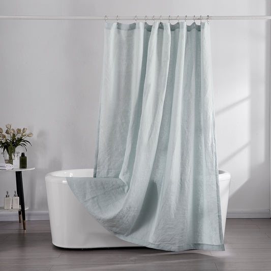 100% linen pale blue shower curtain draped over ceramic bathtub