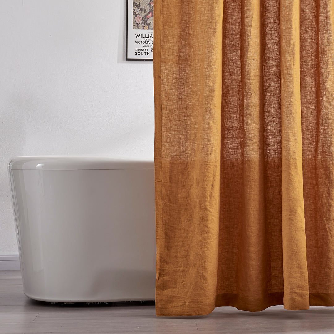 A close-up look of a 100% linen shower curtain in mustard hanging over a ceramic bathtub