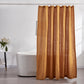 A 100% linen shower curtain in mustard hanging over a ceramic bathtub
