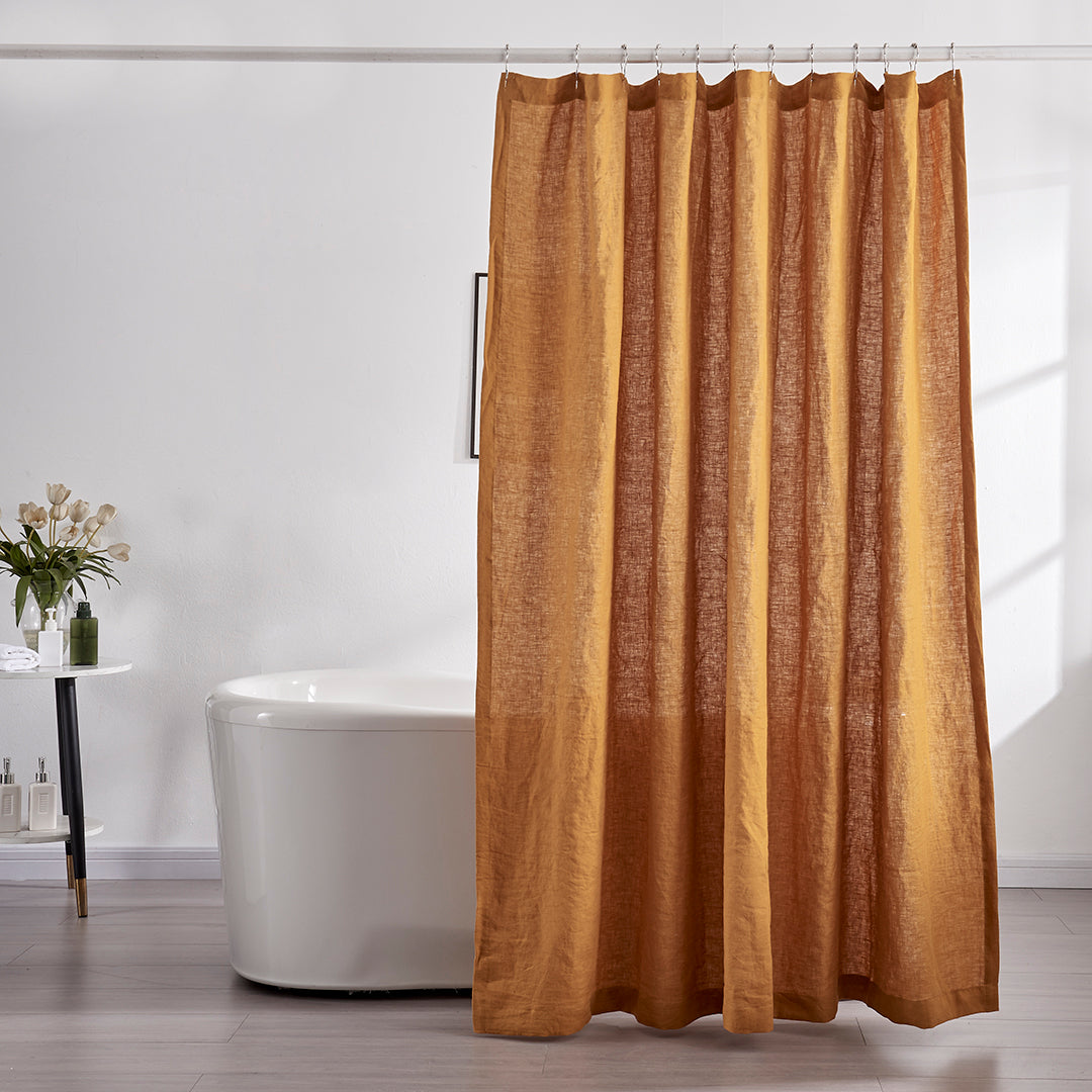 A 100% linen shower curtain in mustard hanging over a ceramic bathtub