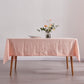 Peach 100% linen tablecloth draped over a wooden table with flower vase