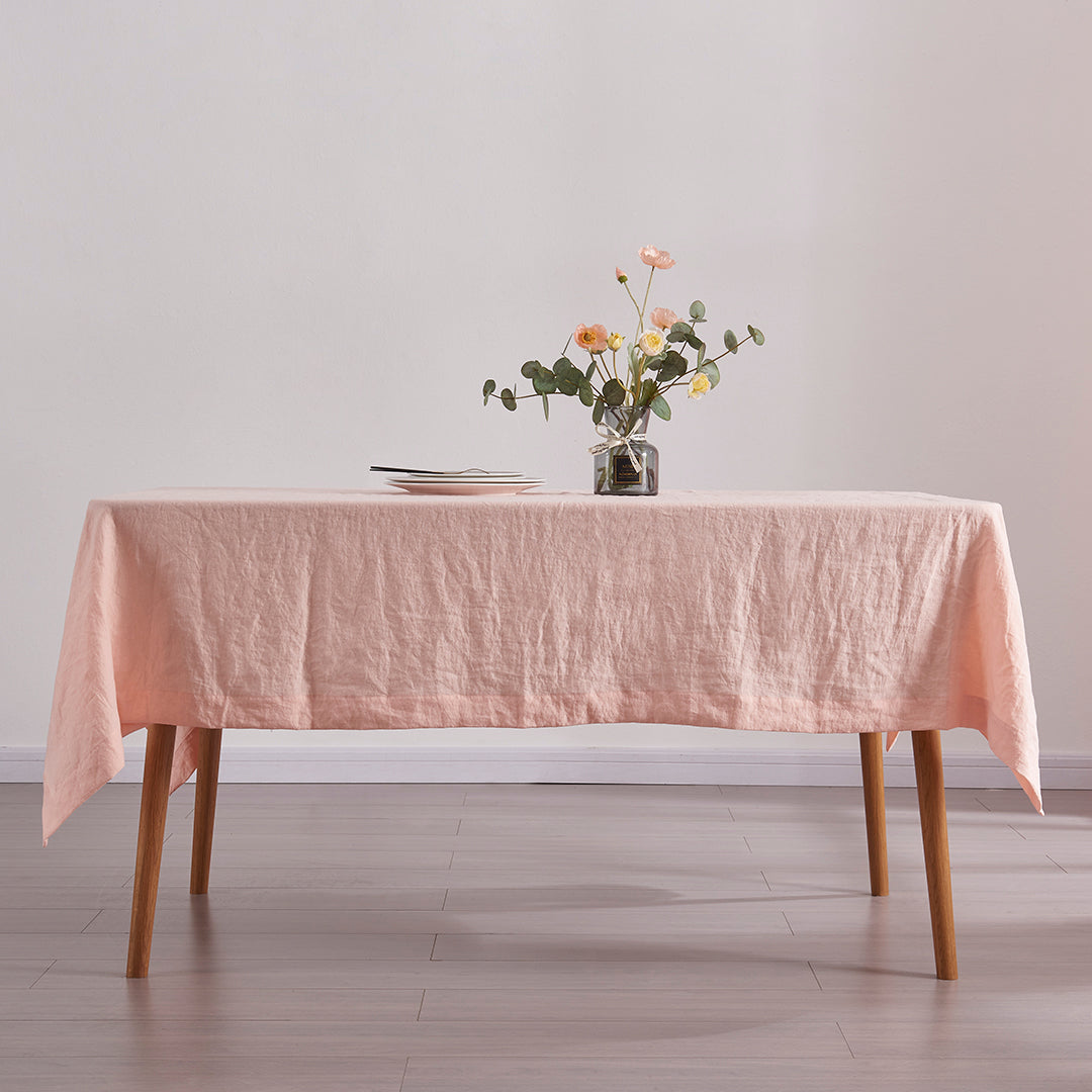 Peach 100% linen tablecloth draped over a wooden table with flower vase