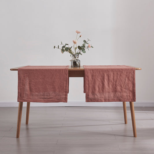 Rust red table runners made from 100% linen draped over a wooden table with flower vase