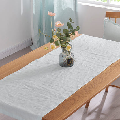 Top angle detail of pale blue pure linen table runner over wooden table