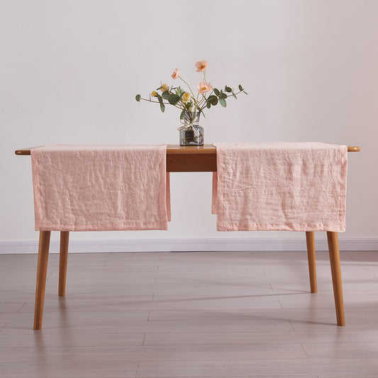 Peach table runners made from 100% linen draped over a wooden table with flower vase