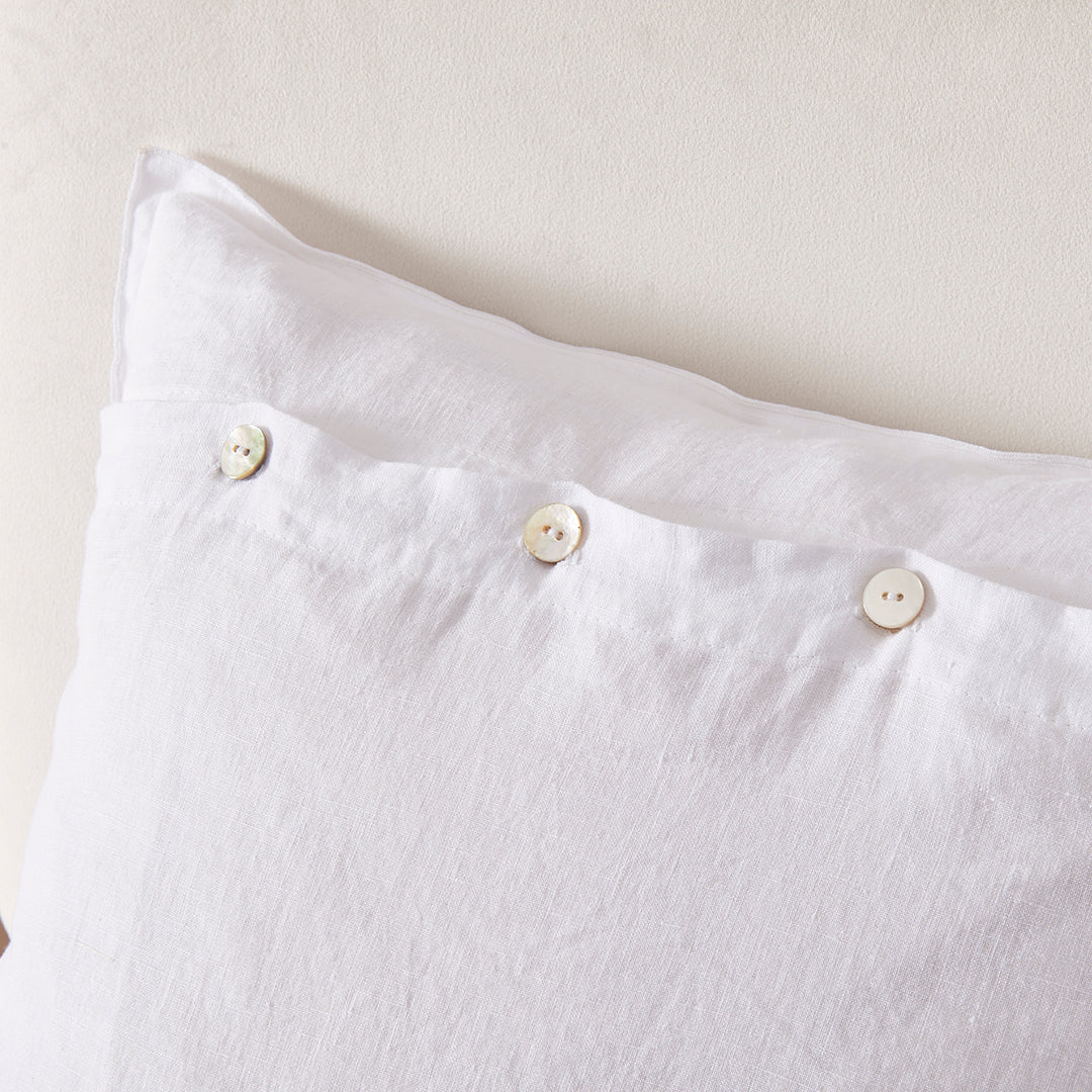 Close-up detail of 100% linen white embroidery cushion cover with mother of pearl buttons