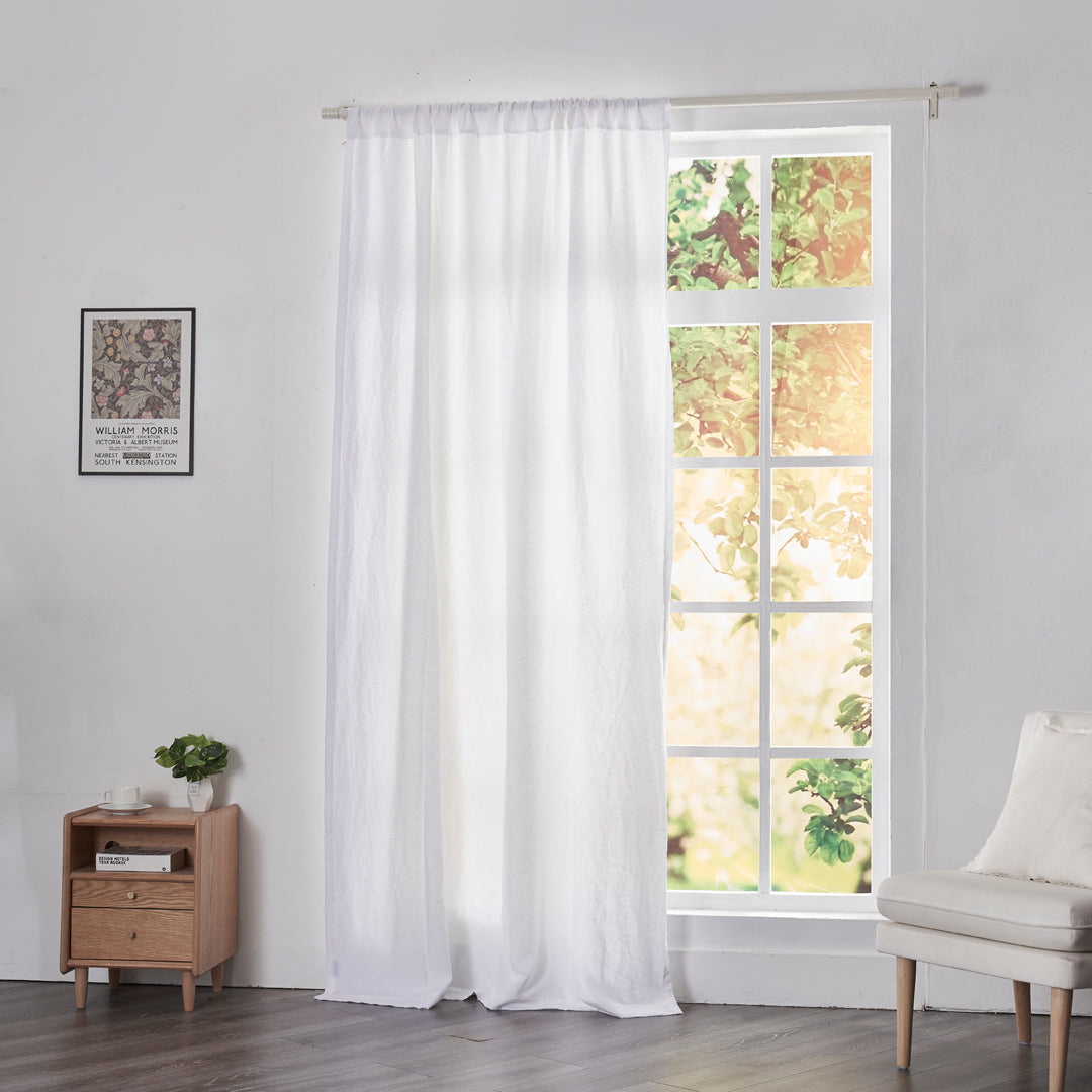 Optic white linen drapery with rod pockets hanging over windows