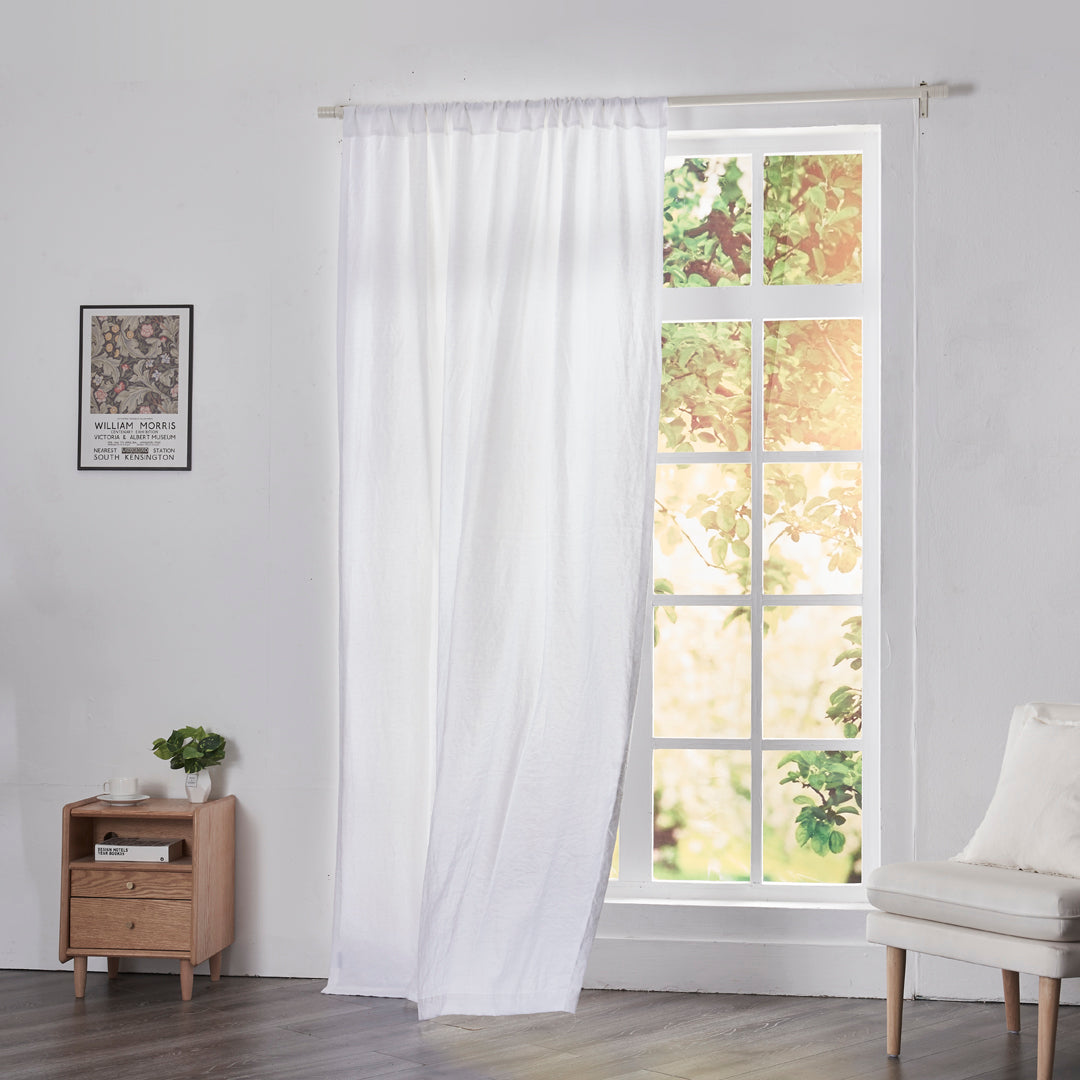 Optic white linen drapery with rod pockets billowing over windows