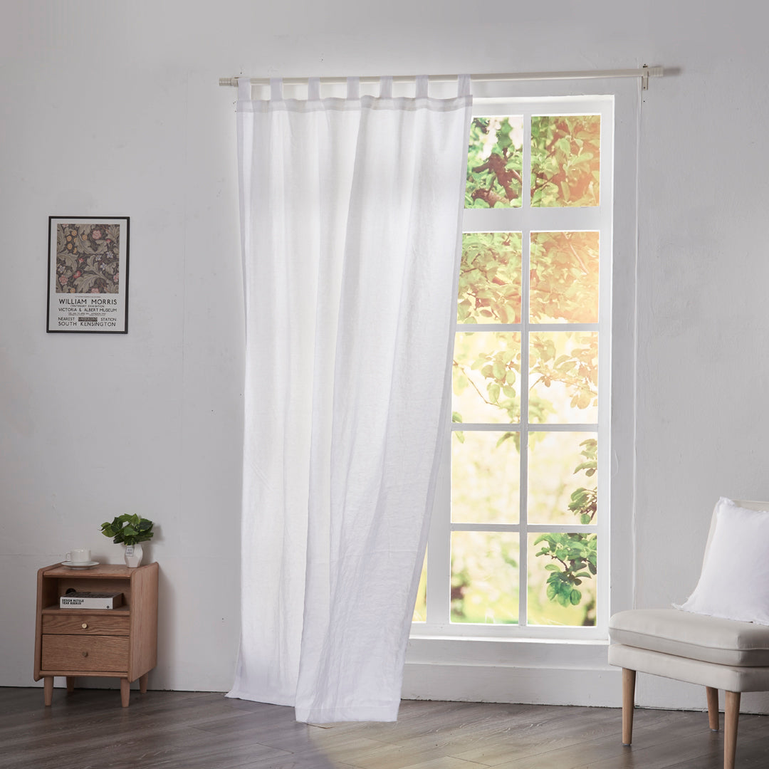 Optic white linen drapery with tab tops billowing over windows