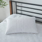 An optic white 100% linen quilted pillowcase on a bed